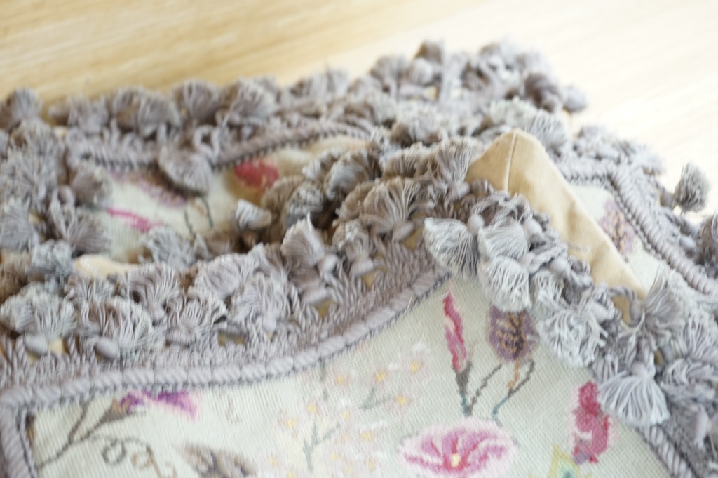 Six small wool worked rectangular cushion covers, designed with roses and trailing flowers on a pale green ground, with mushroom tasselled fringing and velvet backs. 30cm wide x 26cm high. Condition - unused